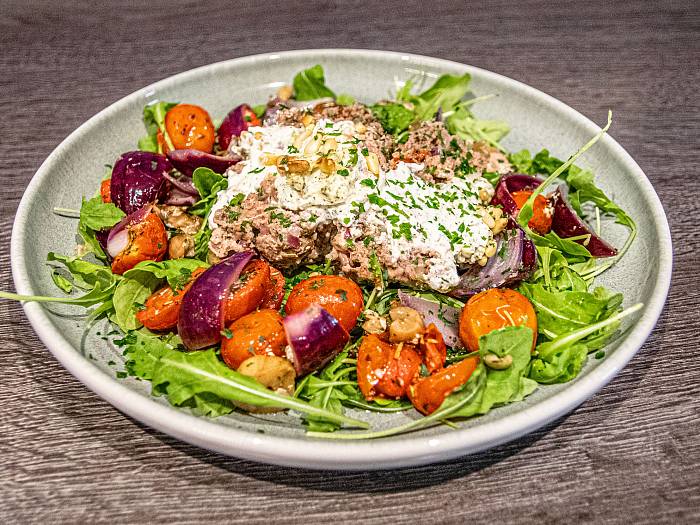 Hackbraten mit Frischkäsefüllung auf buntem Ofengemüse und Rucola