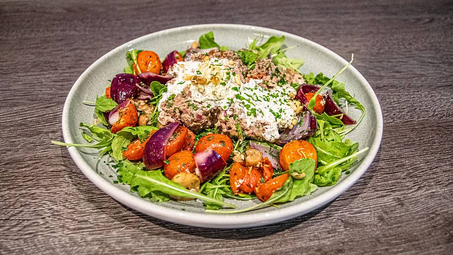 Hackbraten mit Frischkäsefüllung auf buntem Ofengemüse und Rucola