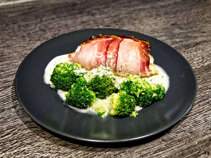 Putenroulade mit Schinken umwickelt, knusprig gebräunt. Im Vordergrund herrlich grüner Brokkoli.