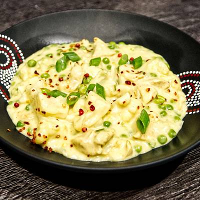 Cremiges Hähnchen Curry mit Blumenkohl, garniert mit frischen Frühlingszwiebelröllchen