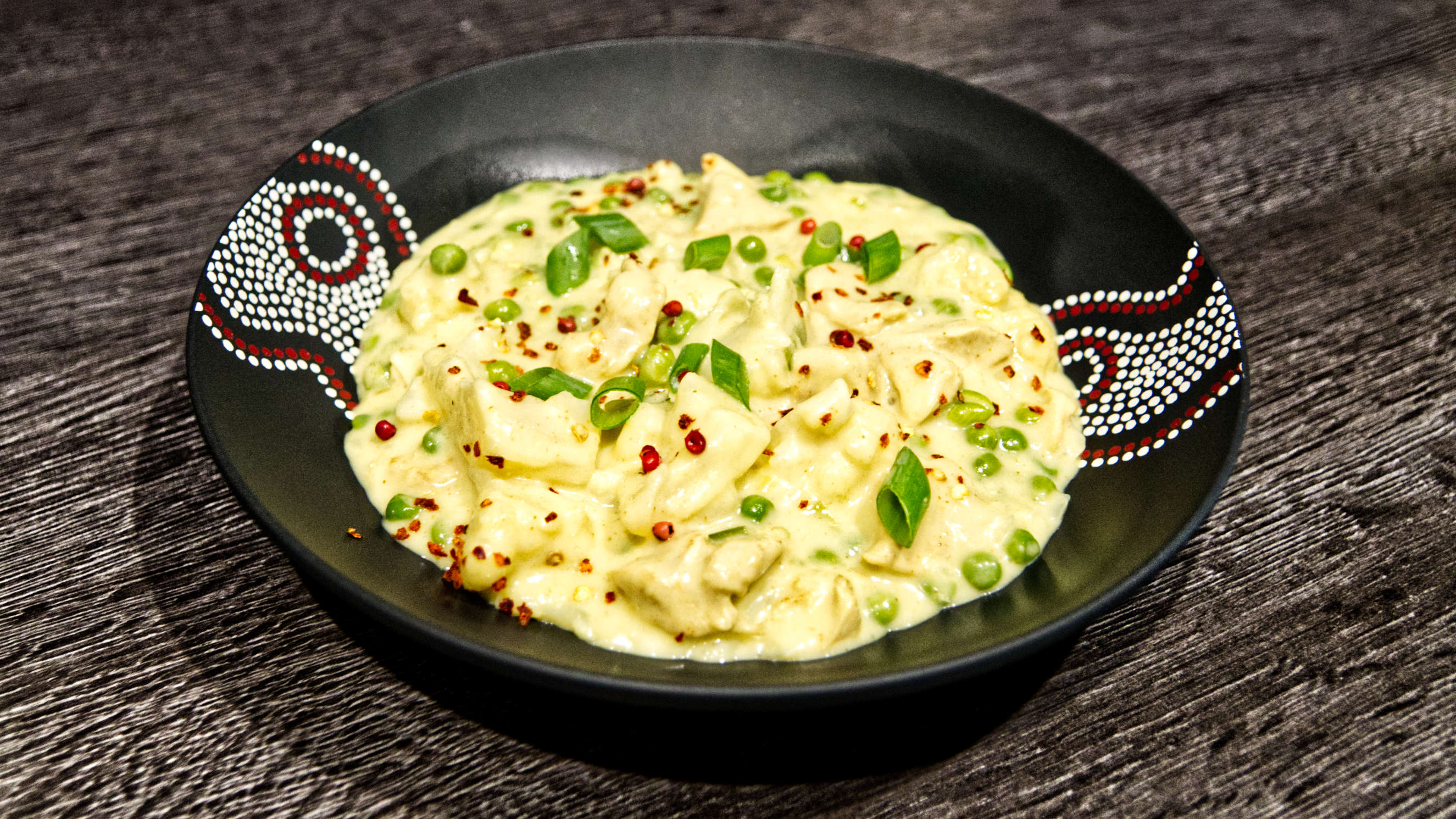 Cremiges Hähnchen Curry mit Blumenkohl, garniert mit frischen Frühlingszwiebelröllchen