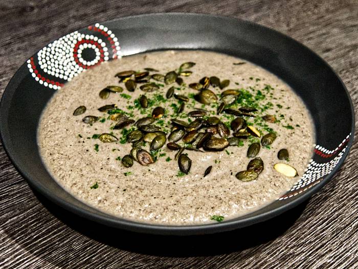 Suppe aus Champignons, püriert; garniert mit Kürbiskernen und Petersilie