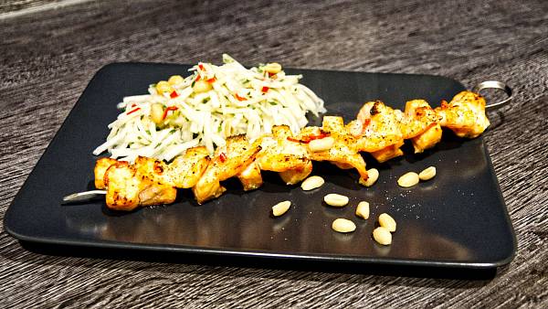 Spieß mit Lachs und Garnelen neben einem Salat aus Kohlrabi