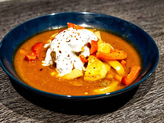 Gulaschsuppe im Teller mit einem Klecks Joghurt.
