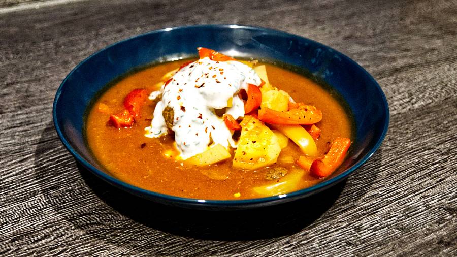 Gulaschsuppe im Teller mit einem Klecks Joghurt.