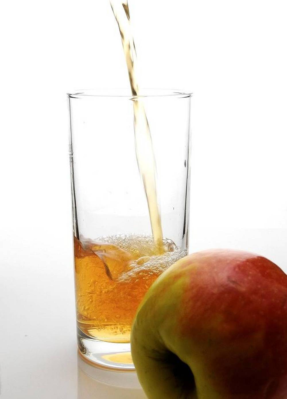 Apfelsaft wird in ein hohes Glas eingegossen. Im Vordergrund liegt ein Apfel, damit man den Apfelsaft nicht mit Pippi verwechselt *lol*.