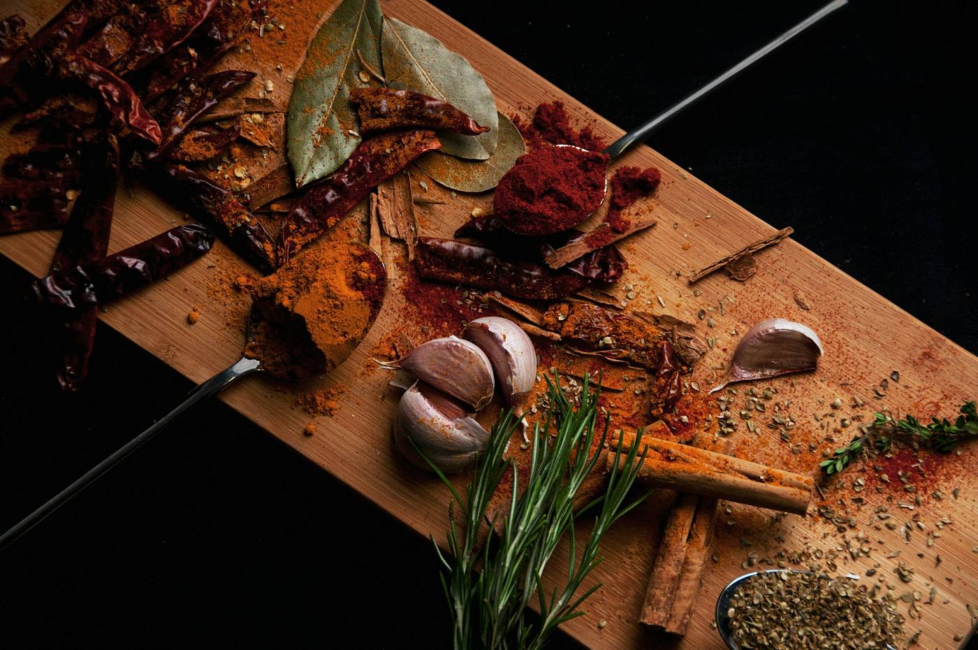 Verschiedene Gewürze, Knoblauch und Kräuter liegen auf deinem Holzbrett.