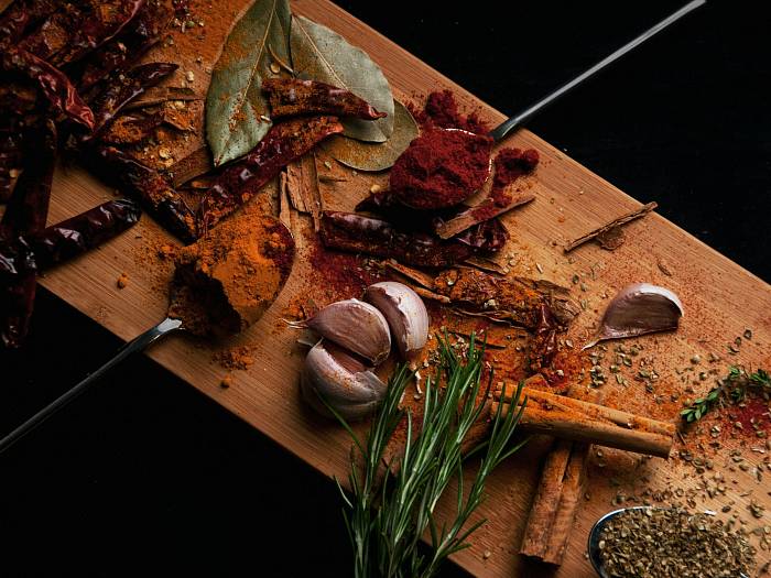 Verschiedene Gewürze, Knoblauch und Kräuter liegen auf deinem Holzbrett.