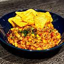One-Pot-Reis-Topf in einem dunklen Teller, dazu liegen Tortilla-Chips dabei.